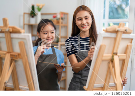 Family time painting together with mother and daughter smiling 126036201