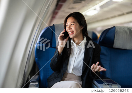 Business travel with woman smiling on phone in an airplane seat 126036248