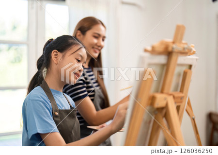 Family time creating art with mother and daughter painting together 126036250