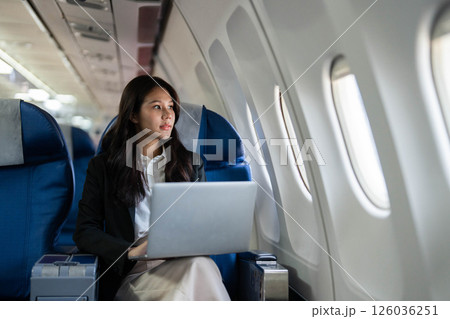 Business travel contemplation with a woman gazing out of the window on a plane Business travel contemplation with a woman gazing out of the window on a plane 126036251
