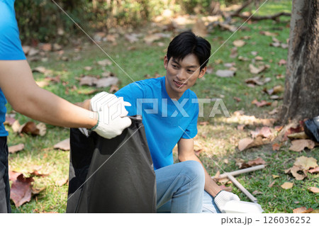 Community engagement. Young man volunteering in park cleanup activity. 126036252