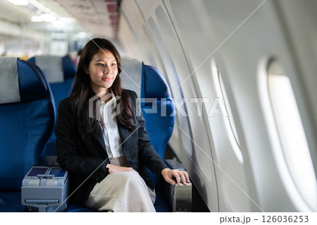 Business travel with young woman sitting thoughtfully on airplane 126036253