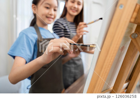 Family time sharing creativity: Mother and daughter painting together 126036258