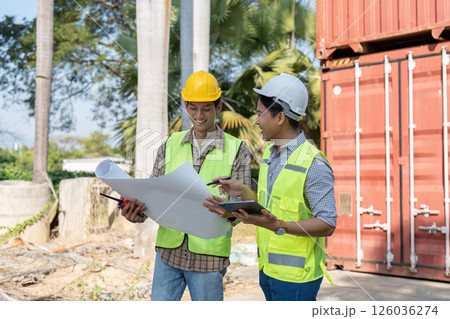 Engineers reviewing logistics plans and collaborating at a shipping container site Engineers reviewing logistics plans and collaborating at a shipping container site 126036274