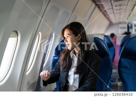 Business travel: Young woman looking out the window on a flight 126036410