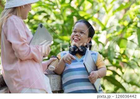 Diverse friends discussing ideas in a sunny park, enjoying their day outside with tablets and headphones Diverse friends discussing ideas in a sunny park, enjoying their day outside with tablets and headphones 126036442