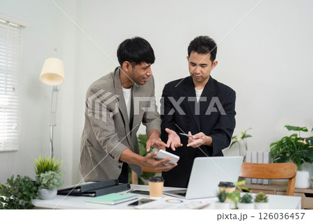 Collaboration and Innovation. Two professionals discussing ideas at a modern workspace, sharing insights on a project. 126036457