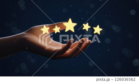 Womans hand gently presenting five shimmering golden star icons floating just above the fingertips, representing a five star rating or review. 126036562