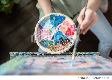 Creative artist mixing vibrant colors on a palette for painting on canvas in a bright studio 126036586