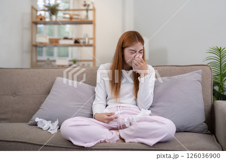 Emotional young woman sitting on sofa, crying with tissues in hand, reflecting on personal struggles Emotional young woman sitting on sofa, crying with tissues in hand, reflecting on personal struggles 126036900