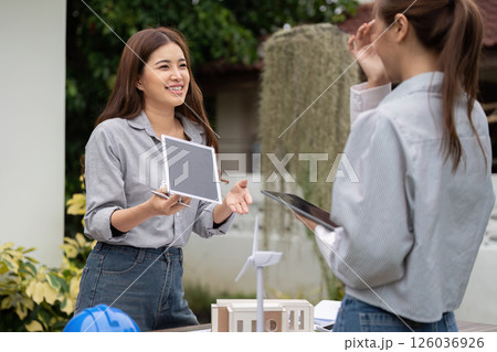 Sustainability and Collaboration. Two women smiling while discussing sustainable architecture concepts outdoors. Sustainability and Collaboration. Two women smiling while discussing sustainable architecture concepts outdoors. 126036926