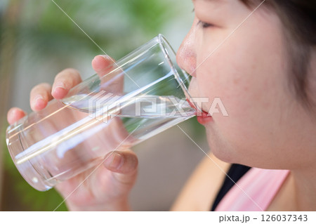 Overweight woman taking a refreshing drink of water from a glass, supporting weight loss and health. Overweight woman taking a refreshing drink of water from a glass, supporting weight loss and health. 126037343