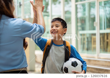 Back to School and Soccer Excitement. A student happily greets a teacher while holding a soccer ball. Back to School and Soccer Excitement. A student happily greets a teacher while holding a soccer ball. 126037616
