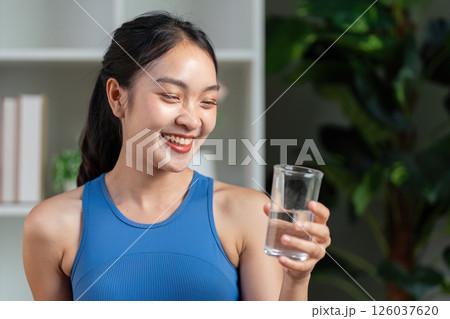 Joyful woman holding a glass of water, celebrating health and hydration in a vibrant environment. Joyful woman holding a glass of water, celebrating health and hydration in a vibrant environment. 126037620