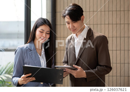 Engaged teamwork. Business professionals reviewing project documentation and digital data in a modern office setting. Engaged teamwork. Business professionals reviewing project documentation and digital data in a modern office setting. 126037621