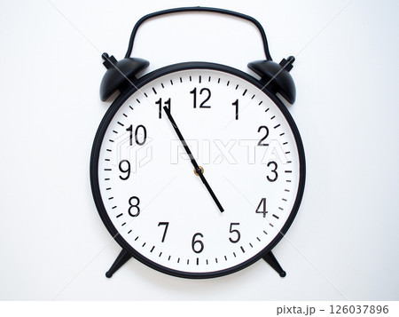 Black Retro Alarm Clock Showing 04:55 or 16:55. Classic Bell Style on White Wood Background. 126037896