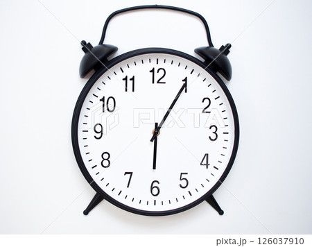 Black Retro Alarm Clock Showing 06:05 or 18:05. Classic Bell Style on White Wood Background. Black Retro Alarm Clock Showing 06:05 or 18:05. Classic Bell Style on White Wood Background. 126037910