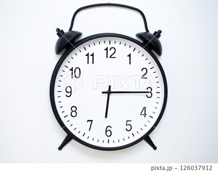 Black Retro Alarm Clock Showing 06:15 or 18:15. Classic Bell Style on White Wood Background. Black Retro Alarm Clock Showing 06:15 or 18:15. Classic Bell Style on White Wood Background. 126037912