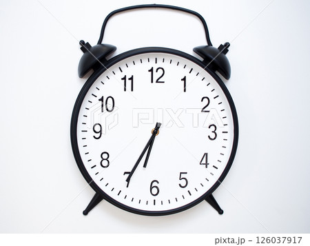 Black Retro Alarm Clock Showing 06:35 or 18:35. Classic Bell Style on White Wood Background. 126037917