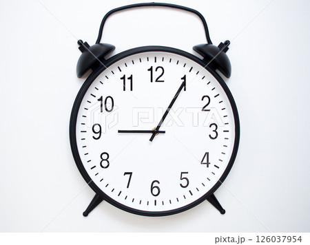 Black Retro Alarm Clock Showing 09:05 or 21:05. Classic Bell Style on White Wood Background. 126037954