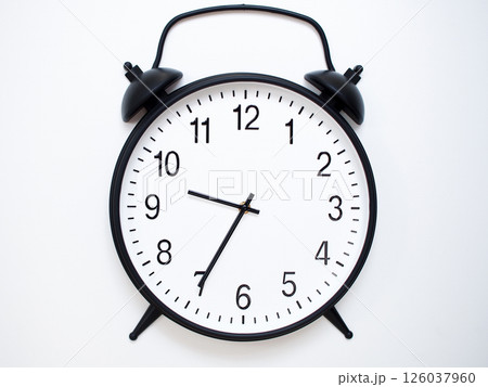 Black Retro Alarm Clock Showing 09:35 or 21:35. Classic Bell Style on White Wood Background. 126037960