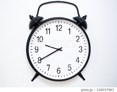 Black Retro Alarm Clock Showing 09:40 or 21:40. Classic Bell Style on White Wood Background. 126037961