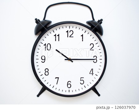 Black Retro Alarm Clock Showing 10:15 or 22:15. Classic Bell Style on White Wood Background. Black Retro Alarm Clock Showing 10:15 or 22:15. Classic Bell Style on White Wood Background. 126037970