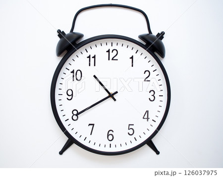 Black Retro Alarm Clock Showing 10:40 or 22:40. Classic Bell Style on White Wood Background. Black Retro Alarm Clock Showing 10:40 or 22:40. Classic Bell Style on White Wood Background. 126037975
