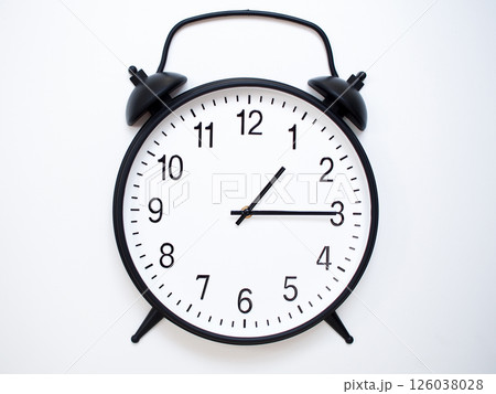 Black Retro Alarm Clock Showing 01:15 or 13:15. Classic Bell Style on White Wood Background. 126038028