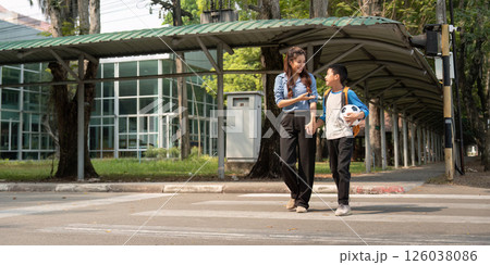 Back to School and Soccer Fun. A mentor and student cross a street, sharing moments with a soccer ball in hand. 126038086