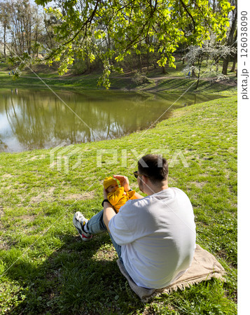 father with newborn son resting near lake 126038090