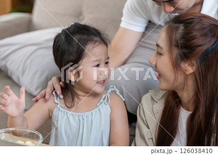 Child enjoying popcorn while engaged with family on a laptop Child enjoying popcorn while engaged with family on a laptop 126038410