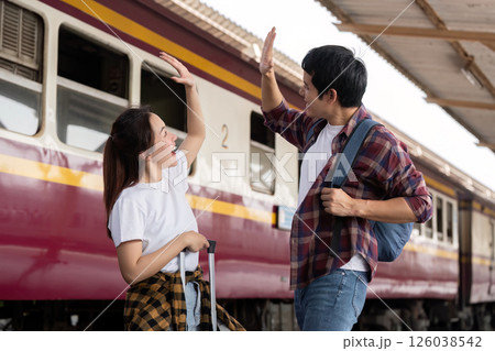Joyful Travel Moments. A couple gives each other a high-five at the train platform. 126038542