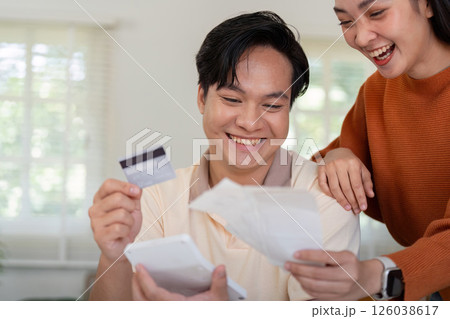 Happy couple celebrating their financial planning, reviewing bills and credit card together. 126038617