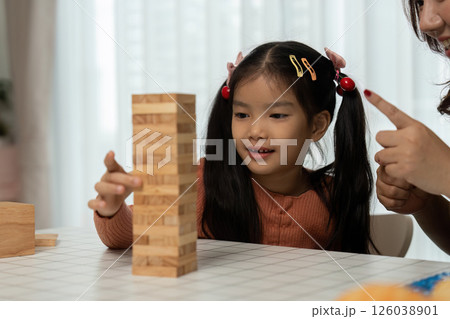 Back to School Activities and Games. A girl focuses on her stacking game with her mother, enhancing her concentration and skills. 126038901