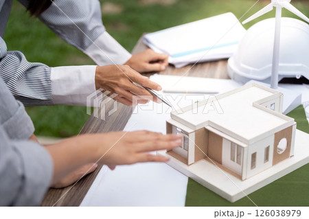 Sustainability and Construction. Professionals examining a model of a sustainable building. 126038979