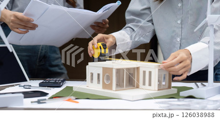 Sustainability and Measurement in Construction. A professional measuring a sustainable building model for accuracy. 126038988
