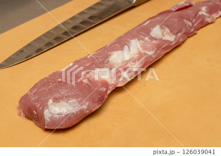 まな板の上でカットしている豚のヒレ肉 ステンレスの包丁が置いていある まな板の上でカットしている豚のヒレ肉 ステンレスの包丁が置いていある 126039041
