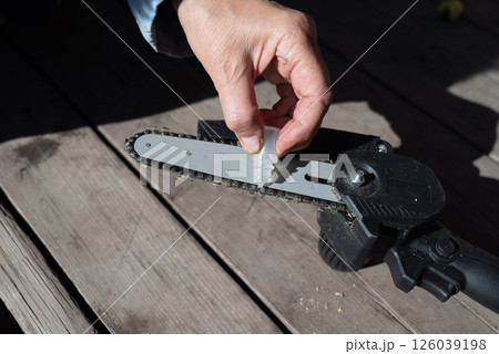 A man repairs an electric saw. Lubrication of the chain. 126039198
