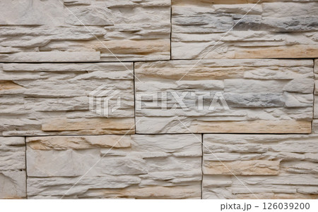 Textured stone wall featuring a natural, rustic design with warm tones and intricate patterns in a contemporary setting 126039200
