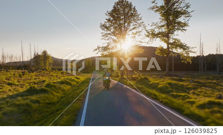 Motorcycle Rider in a Beautiful Sunset Rural Landscape. Action Sports Shot of Touring Motorbike. Motorcycle Rider in a Beautiful Sunset Rural Landscape. Action Sports Shot of Touring Motorbike. 126039825