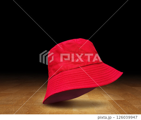 Red bucket hat on wooden floor, black background. Red bucket hat on wooden floor, black background. 126039947