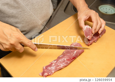 豚ヒレ肉を一口大にカットしている男性料理人の手元 126039954