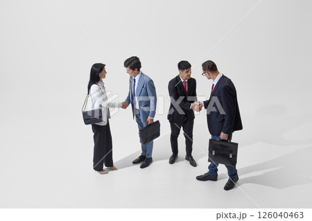 Colleagues shake hands against white studio background, representing diplomatic agreements and business partnerships in action. 126040463