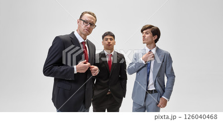 Confident businessmen in suits stand against white backdrop, embodying business professionalism and policy influence. 126040468