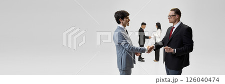 Banner. Successful business negotiation concludes with handshakes against white studio backdrop, demonstrating diplomatic success. 126040474
