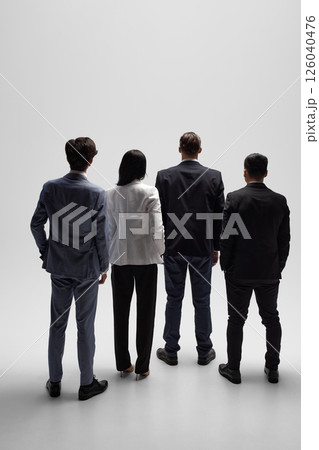 Back view photo of professionals stand looking forward against white studio backdrop, prepared for business negotiations. 126040476