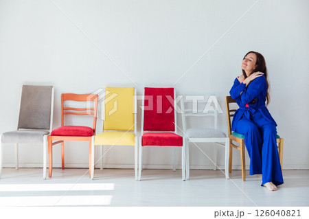 A woman in a suit and many chairs in the interior of a white room 126040821
