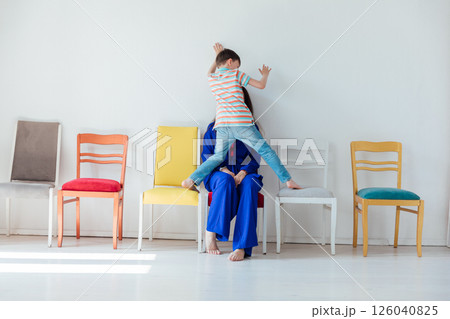 Woman and boy sitting on different chairs in white room 126040825