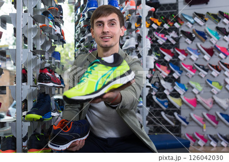 Customer proudly presenting chosen sneaker in sports store Customer proudly presenting chosen sneaker in sports store 126042030